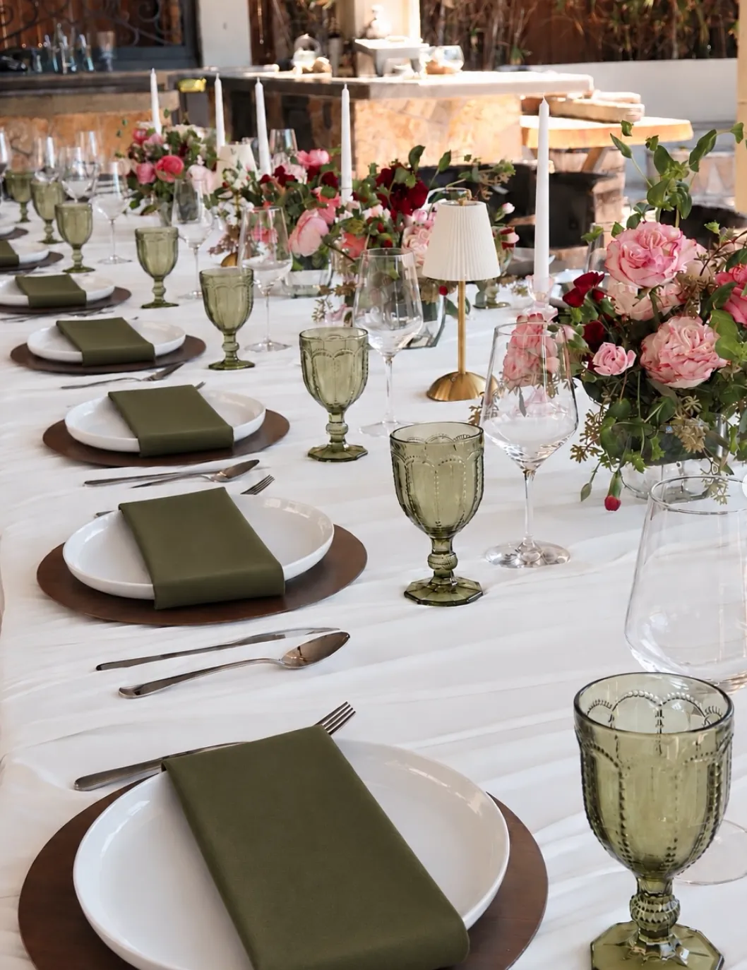 Long table with olive-green goblets, walnut chargers and pink roses